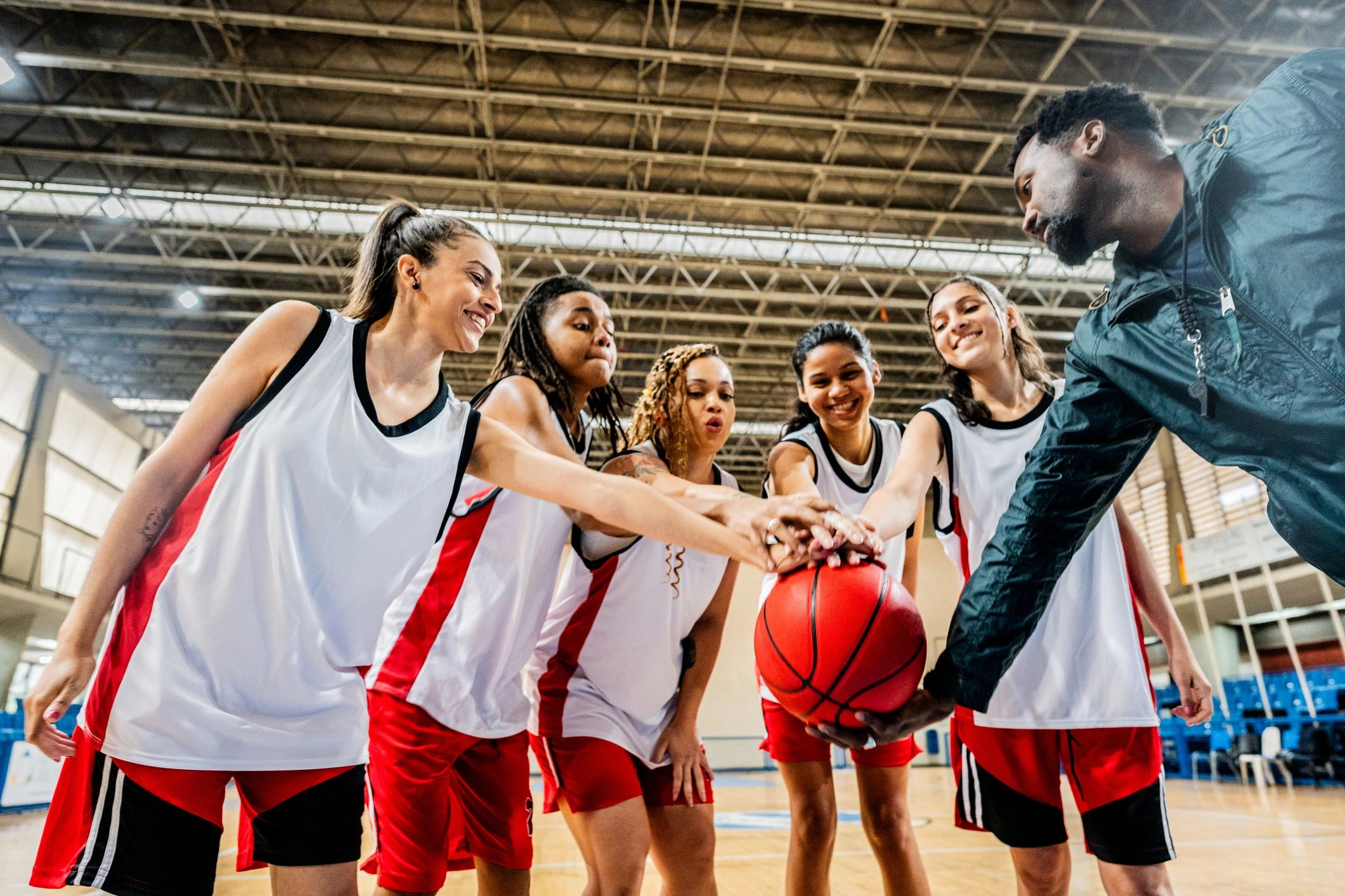 Basketball coach and players joining hands on the court
