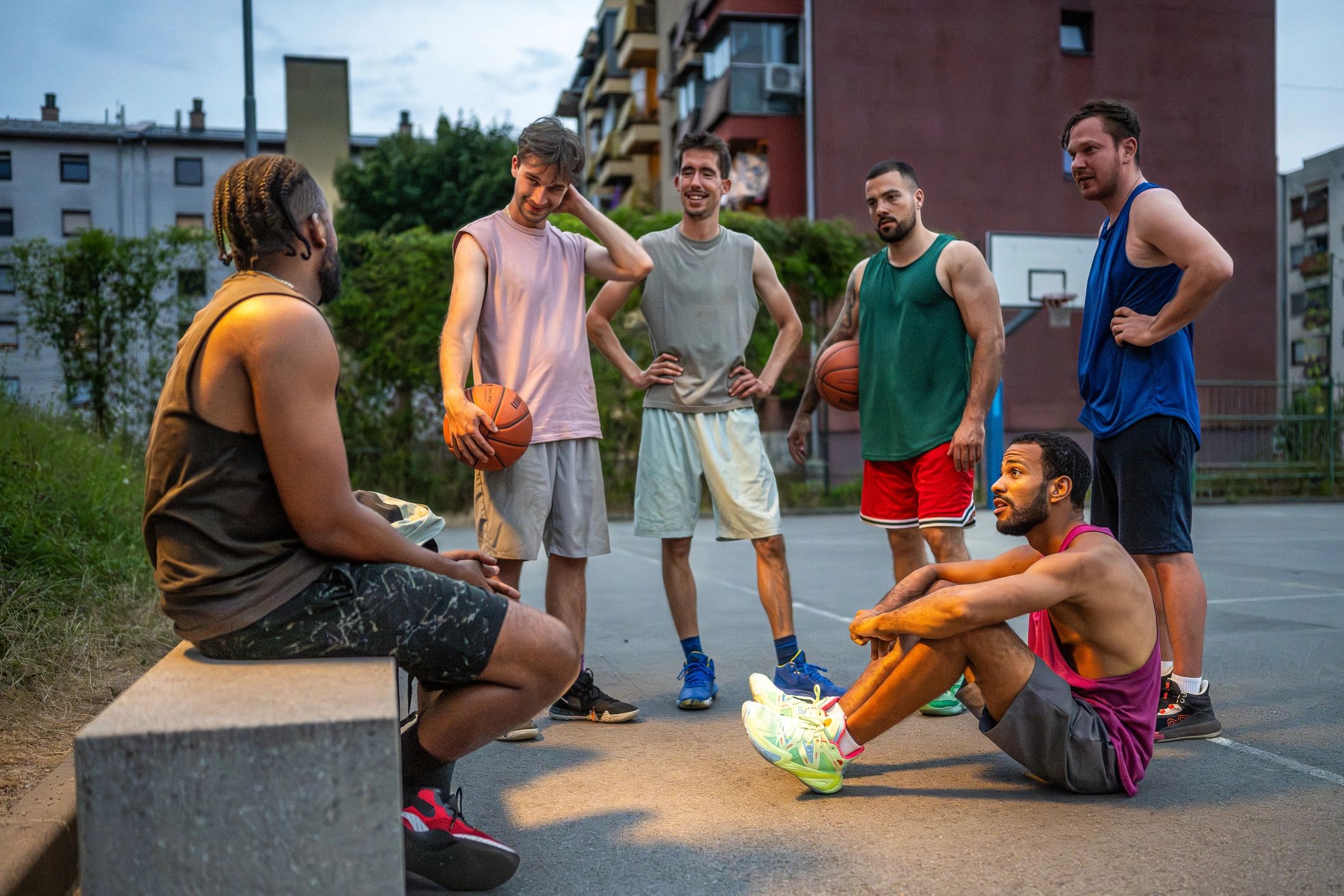 Basketball players gathered on an outdoor court